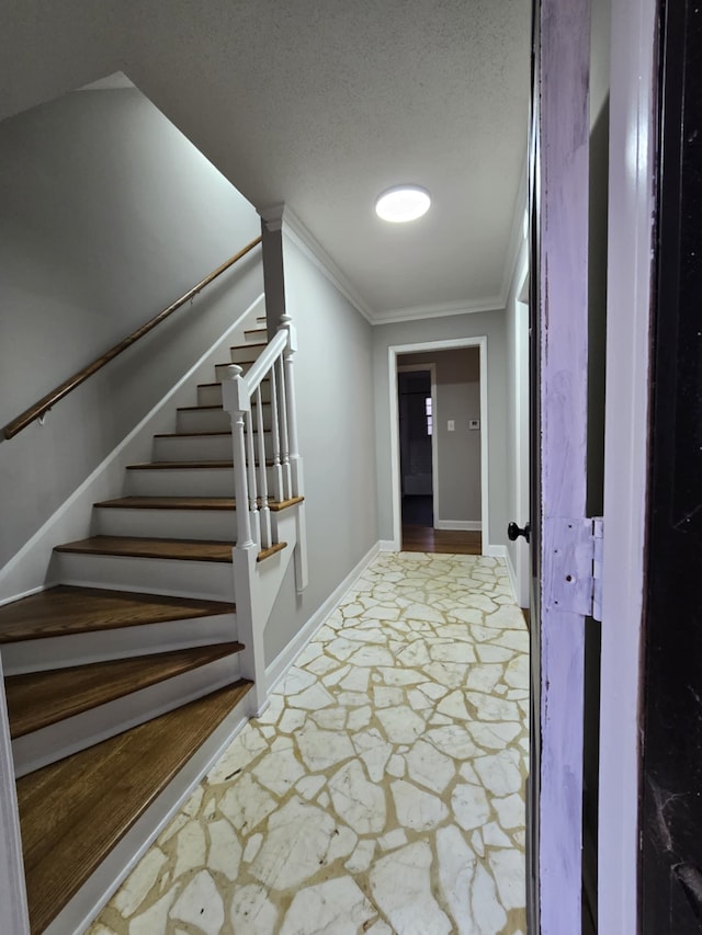 corridor with a textured ceiling, baseboards, stairs, stone finish floor, and crown molding