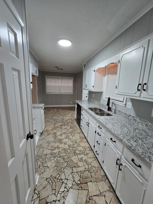 kitchen with a textured ceiling, a sink, white cabinetry, black dishwasher, and light stone countertops