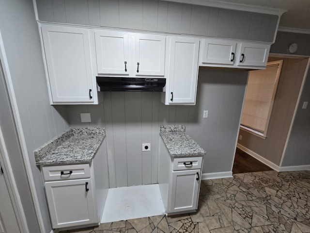 kitchen with light stone countertops, white cabinetry, and under cabinet range hood