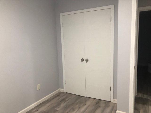 unfurnished bedroom featuring a closet, wood finished floors, and baseboards