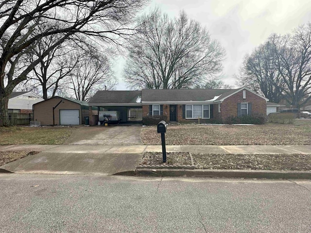 view of front of house featuring driveway, brick siding, and an outbuilding