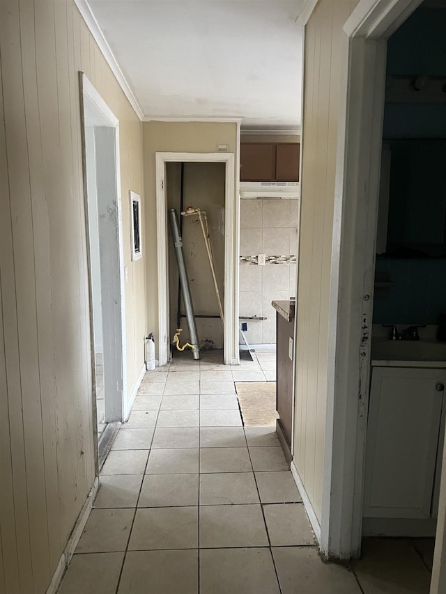 hall featuring wooden walls, light tile patterned flooring, a sink, and crown molding