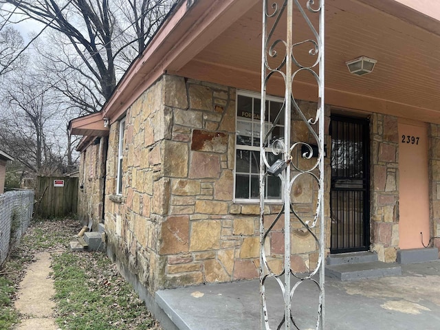 property entrance with stone siding and fence