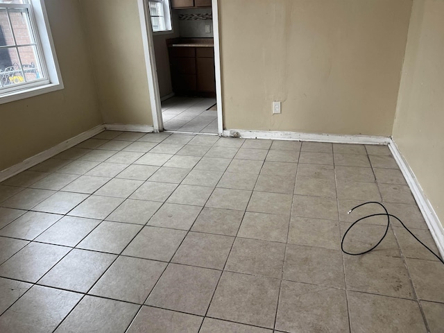 unfurnished room featuring light tile patterned floors and baseboards