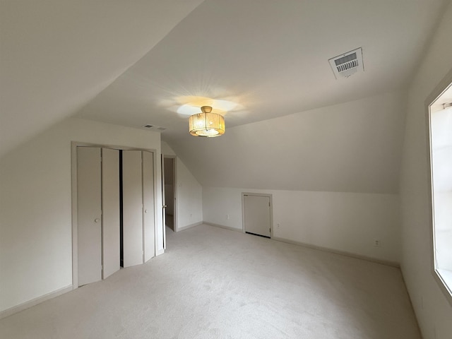 additional living space featuring light colored carpet, visible vents, vaulted ceiling, and baseboards