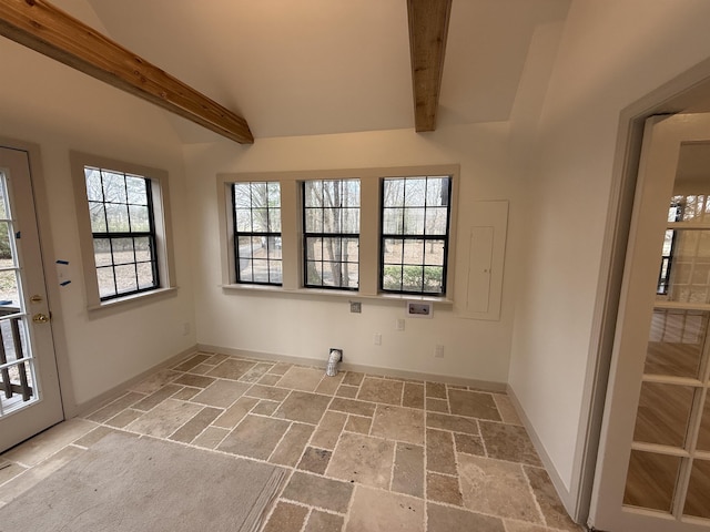 interior space with vaulted ceiling with beams, a healthy amount of sunlight, stone tile floors, and baseboards