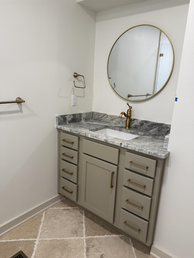 bathroom featuring stone finish floor, vanity, and baseboards