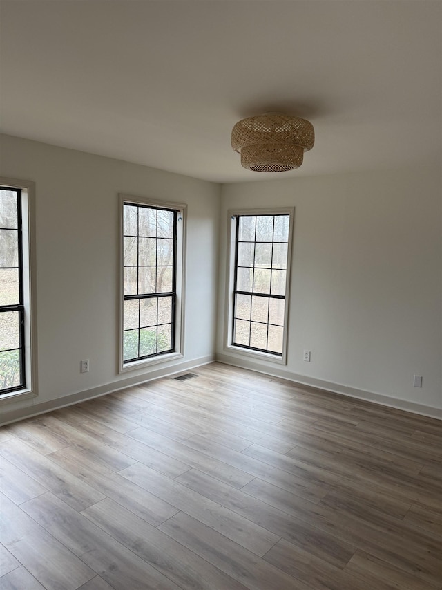 unfurnished room with a healthy amount of sunlight, light wood-style flooring, and baseboards