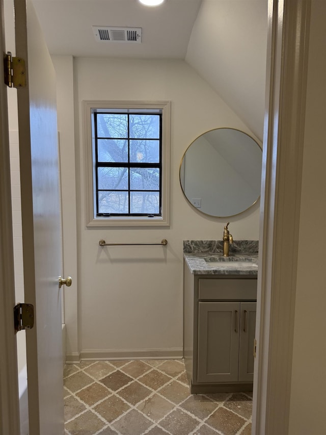 bathroom with visible vents, vaulted ceiling, vanity, and baseboards