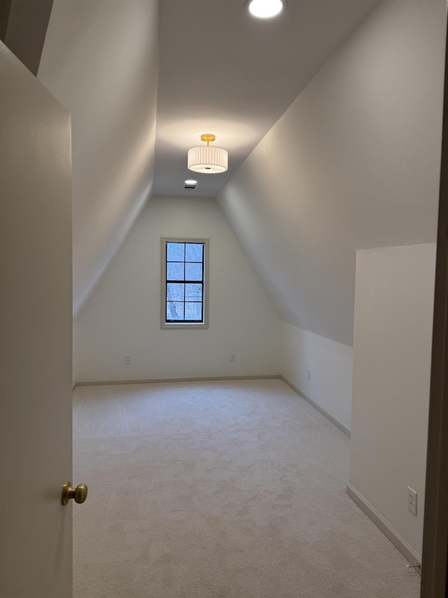 additional living space with lofted ceiling, light carpet, and baseboards