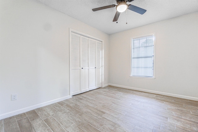 unfurnished bedroom with a closet, light wood-style flooring, baseboards, and a textured ceiling