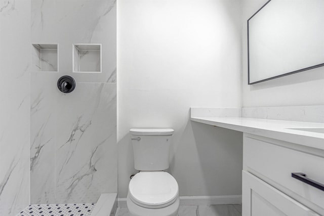 bathroom with toilet, vanity, baseboards, marble finish floor, and a shower stall