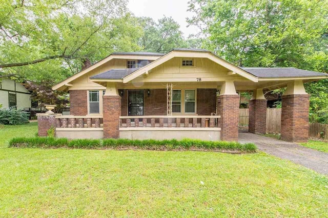 craftsman-style home with a porch, brick siding, fence, driveway, and a front yard