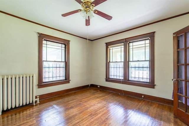 spare room featuring dark wood-style floors, radiator heating unit, plenty of natural light, and crown molding