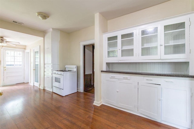 kitchen with visible vents, dark wood finished floors, white cabinets, glass insert cabinets, and gas range gas stove