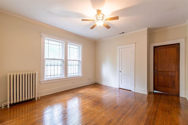 unfurnished bedroom with baseboards, radiator heating unit, dark wood finished floors, and crown molding