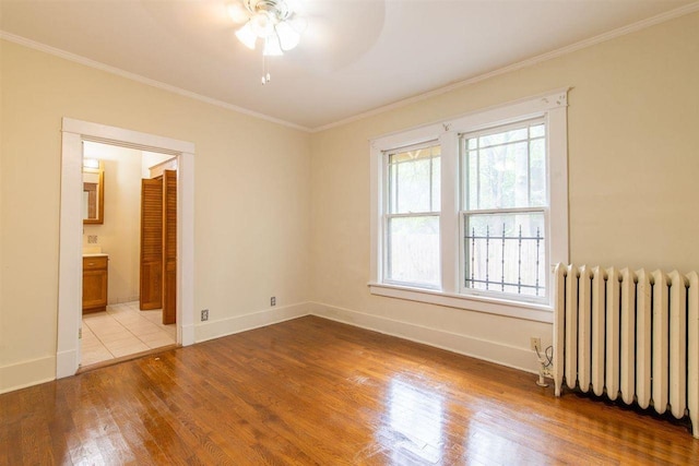 spare room featuring ornamental molding, light wood finished floors, and radiator heating unit