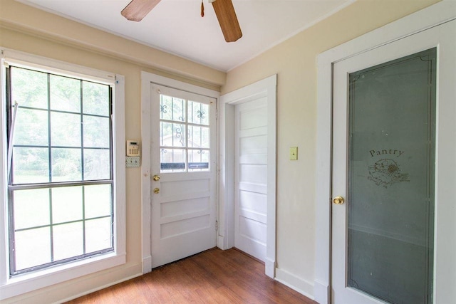 doorway to outside with wood finished floors, a ceiling fan, and baseboards