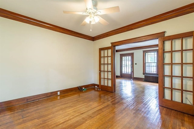 spare room featuring french doors, radiator, ornamental molding, light wood-type flooring, and baseboards