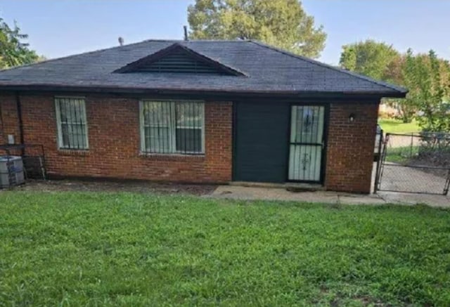 rear view of property with central air condition unit, fence, a lawn, and brick siding