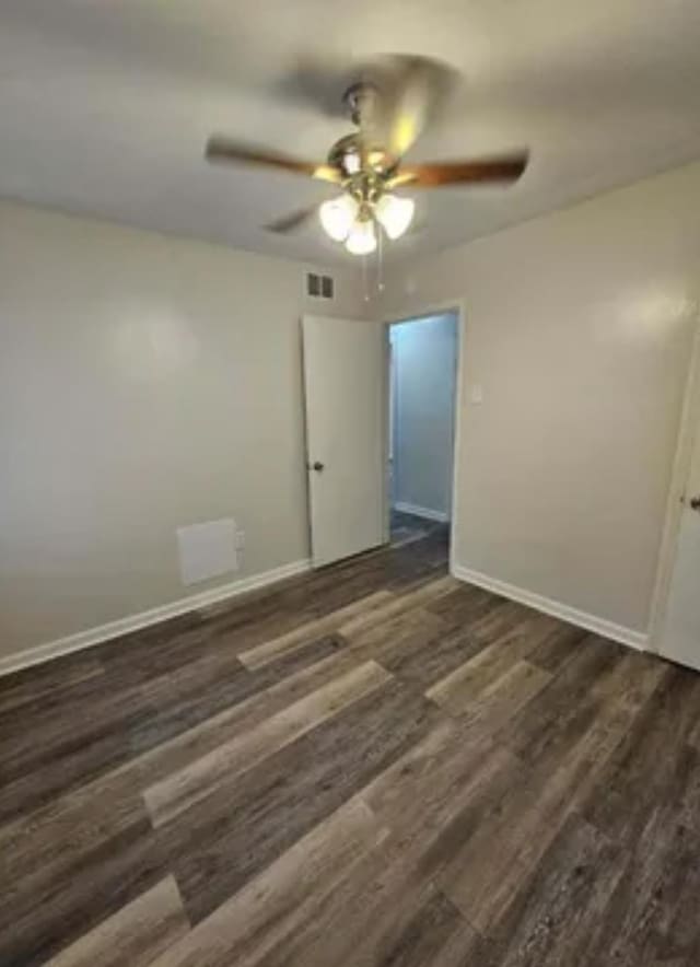 unfurnished bedroom featuring ceiling fan, dark wood-style flooring, visible vents, and baseboards