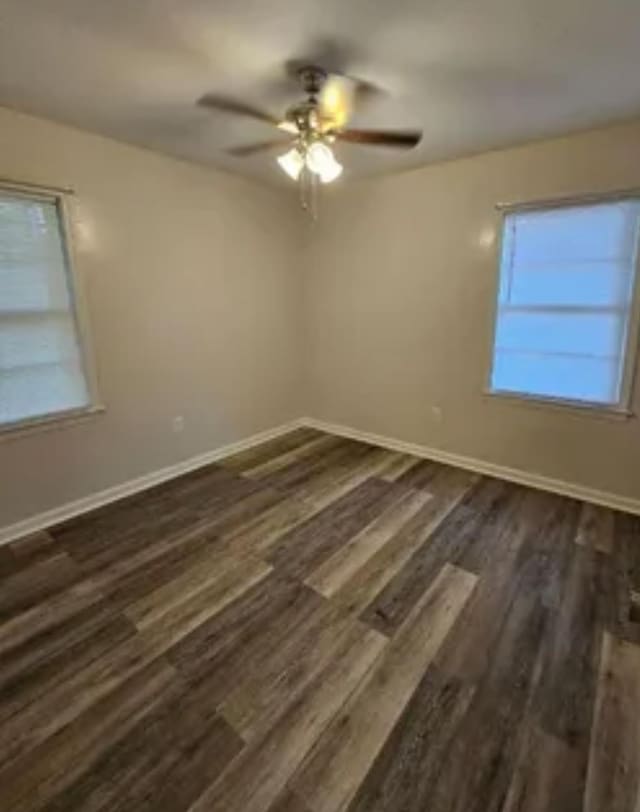 spare room with dark wood-style floors, baseboards, and a ceiling fan