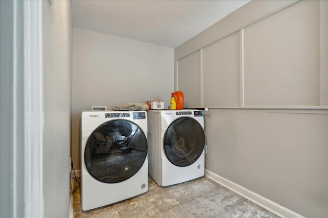 laundry area with laundry area, baseboards, washer and clothes dryer, and a textured ceiling