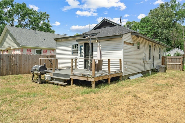 rear view of house featuring a deck, a yard, and fence