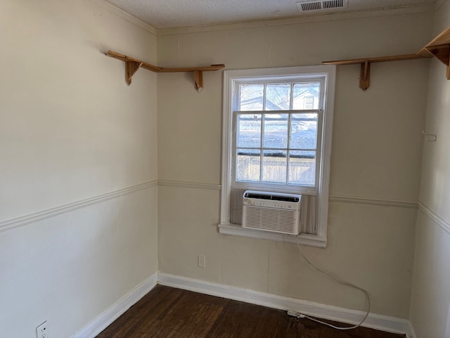 empty room featuring dark wood finished floors, visible vents, a textured ceiling, cooling unit, and baseboards