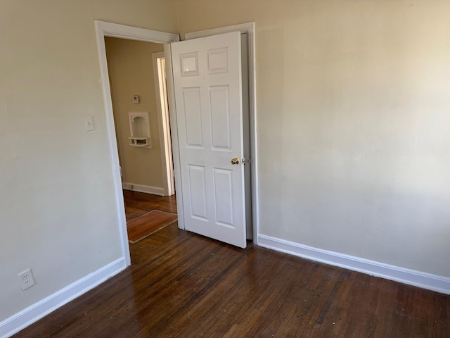 spare room with dark wood-style flooring and baseboards