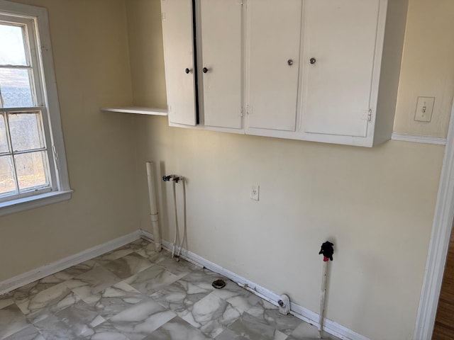 laundry room featuring marble finish floor, cabinet space, and baseboards