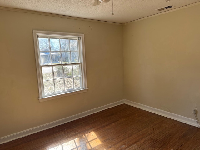 spare room featuring visible vents, a textured ceiling, baseboards, and wood finished floors