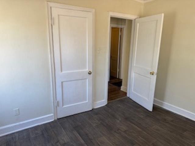 unfurnished bedroom with dark wood-style flooring and baseboards