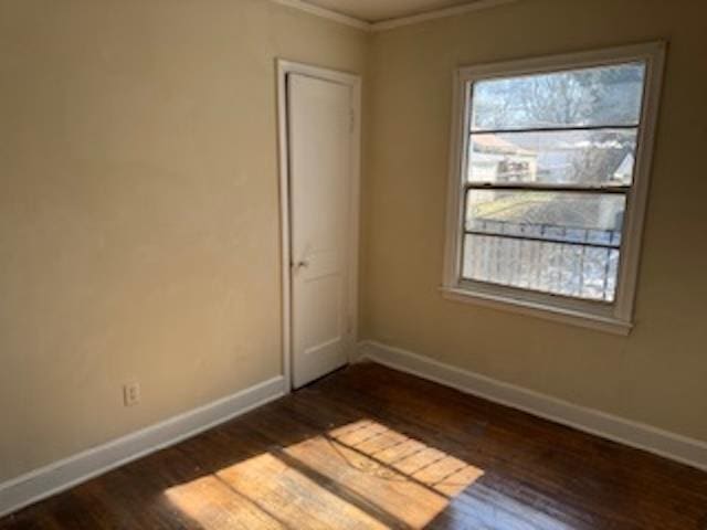 spare room with dark wood-style floors, ornamental molding, and baseboards