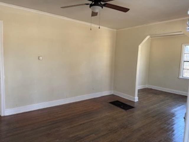 spare room featuring dark wood-type flooring, crown molding, baseboards, and a ceiling fan