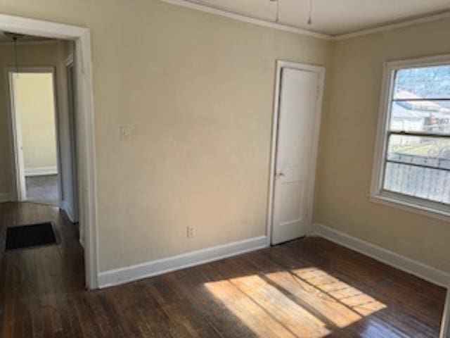 spare room featuring a ceiling fan, baseboards, dark wood finished floors, and crown molding