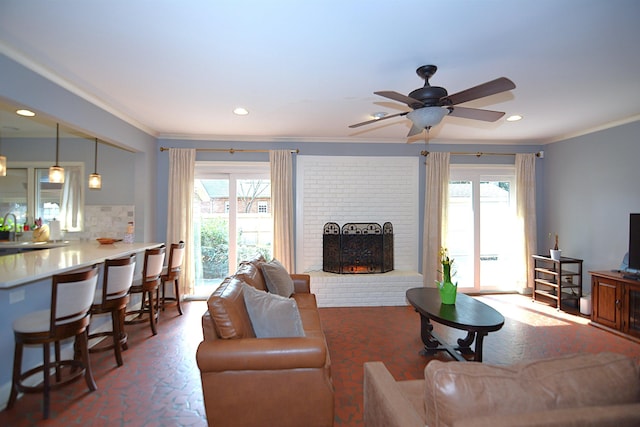 living room with a brick fireplace, ornamental molding, and a wealth of natural light