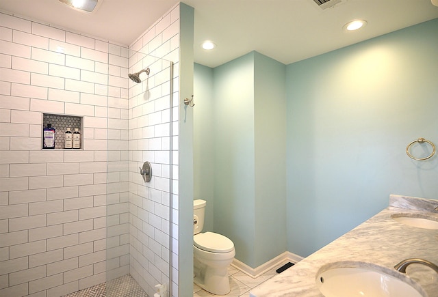 full bath with a tile shower, a sink, toilet, and baseboards