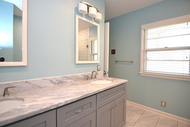 bathroom with double vanity, marble finish floor, baseboards, and a sink