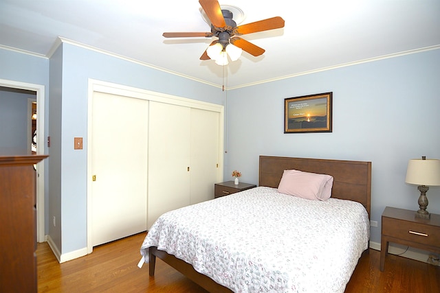 bedroom featuring crown molding, a closet, baseboards, and wood finished floors