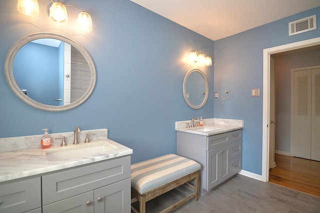 full bathroom with two vanities, a sink, visible vents, and baseboards