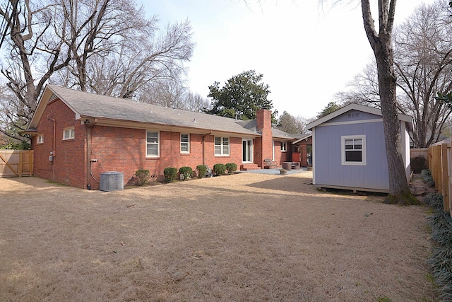 rear view of property featuring an outbuilding, brick siding, a chimney, and fence