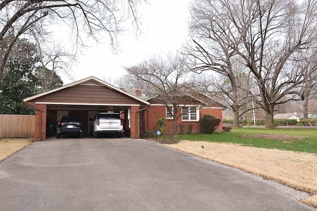 ranch-style home featuring a chimney, aphalt driveway, a front lawn, a carport, and brick siding