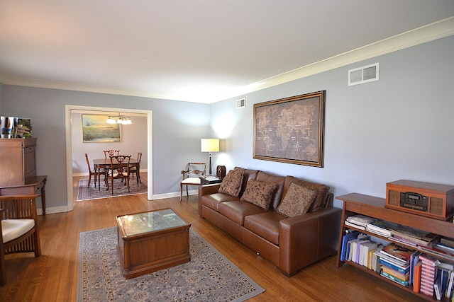 living area featuring baseboards, wood finished floors, visible vents, and crown molding