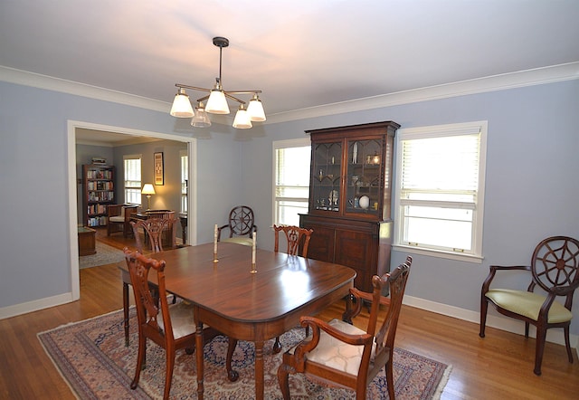 dining area with ornamental molding, an inviting chandelier, baseboards, and wood finished floors