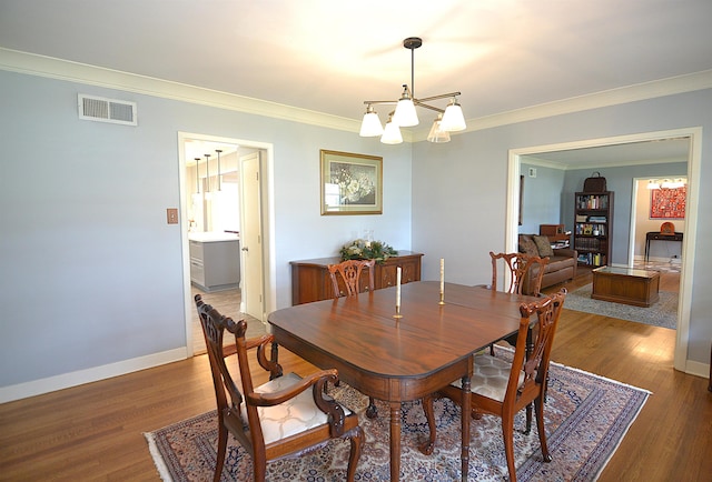 dining room featuring baseboards, visible vents, dark wood finished floors, ornamental molding, and a chandelier