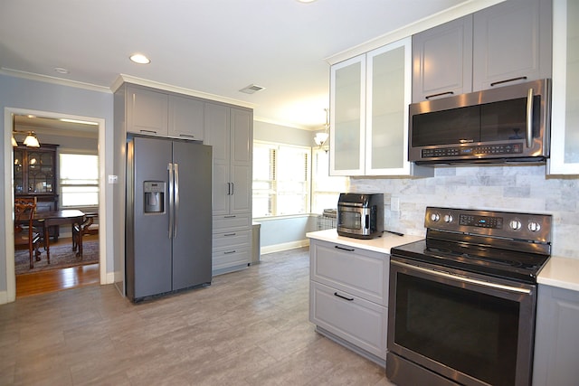 kitchen with glass insert cabinets, stainless steel appliances, light countertops, and gray cabinetry