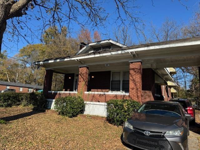 view of front of house featuring brick siding, a front lawn, and a porch