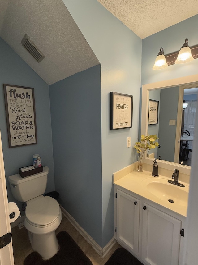 bathroom with visible vents, lofted ceiling, toilet, a textured ceiling, and vanity