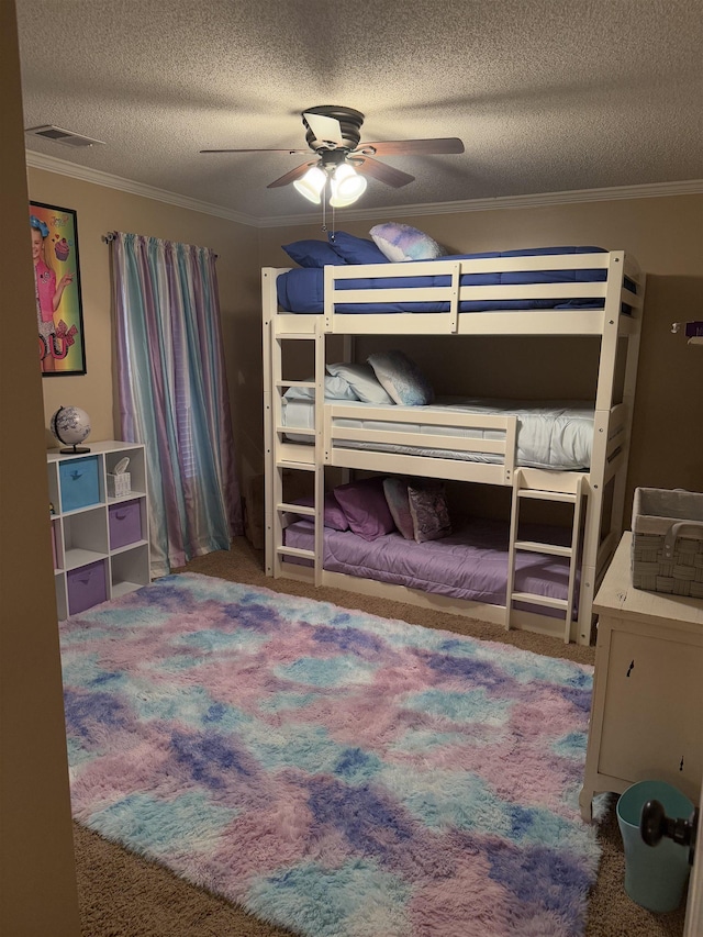 carpeted bedroom featuring a textured ceiling, ornamental molding, visible vents, and a ceiling fan